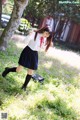 A woman in a school uniform is walking through a field of flowers.