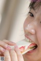 A young girl eating a sandwich with a strawberry on it.