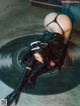 A woman in a black latex outfit laying on a vinyl record.