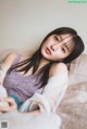 A woman laying on top of a bed next to a pillow.