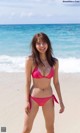 A woman in a pink bikini standing on a beach.