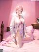 A woman in a pink lingerie sitting on a bed.
