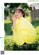 A woman in a yellow kimono sitting in a field of flowers.