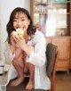 A woman sitting on a chair eating an apple.