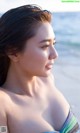 A woman standing on a beach next to the ocean.