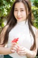 A young woman holding a red flower in her hand.