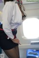 A woman in a white shirt and black skirt on an airplane.