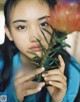 A woman holding a flower in front of her face.