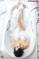 A woman laying in a bathtub covered in foam.