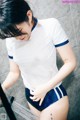 A woman in a white shirt and blue shorts standing in a shower.