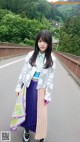 A woman standing on the side of a road holding a scarf.