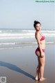 A woman in a pink bikini standing on a beach.