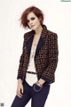 A woman in a tweed jacket and pants posing for a picture.