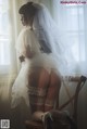 A woman in a wedding dress sitting on a chair.