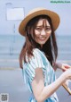 A woman wearing a straw hat standing on a beach.