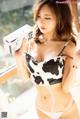 A woman in a cow print bikini holding a box of milk.