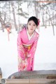 A woman in a pink kimono standing in the snow.