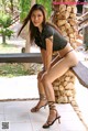 A woman in a black bikini sitting on a stone bench.